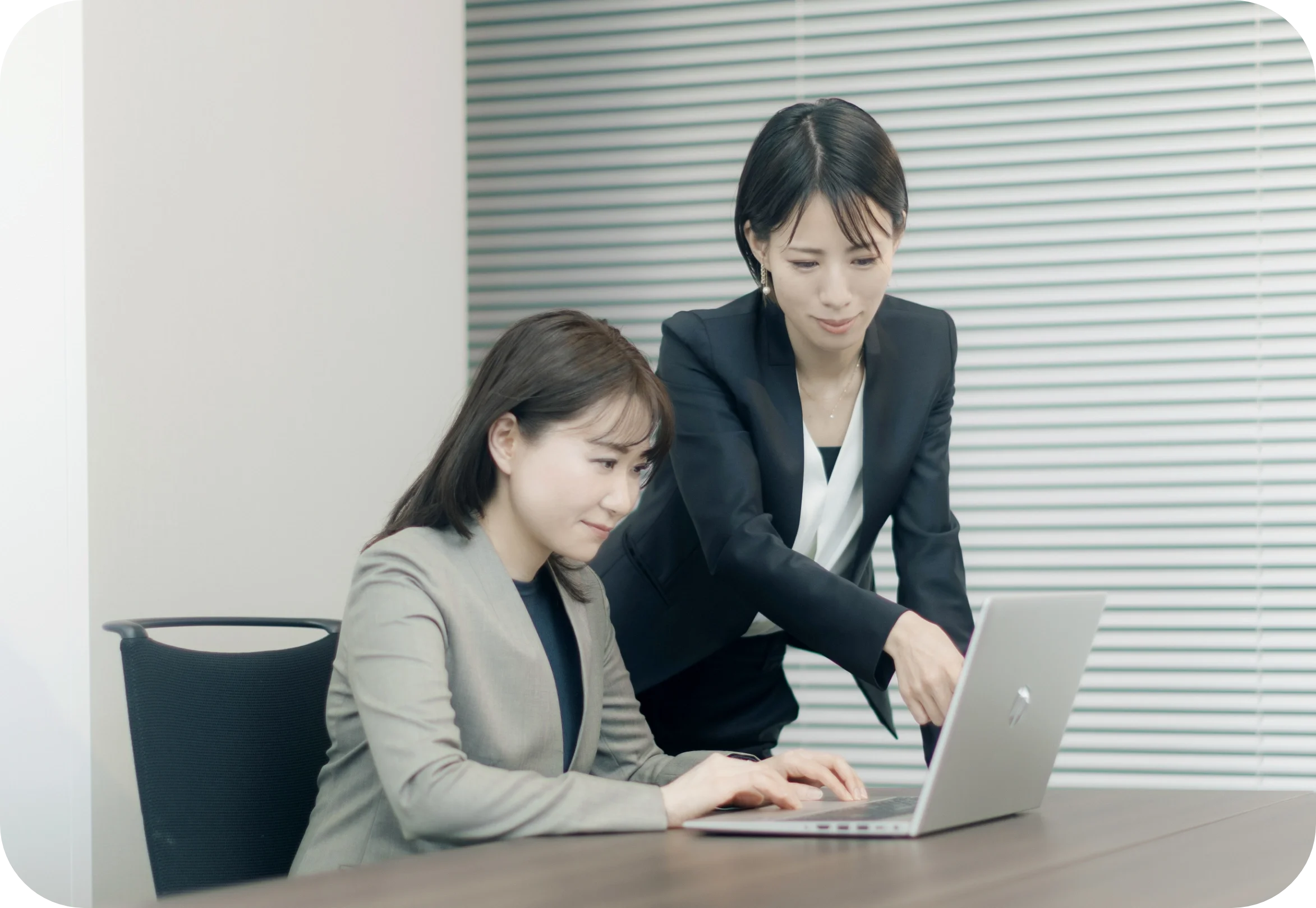 手元にパソコンがあり、同僚にはにかむ女性